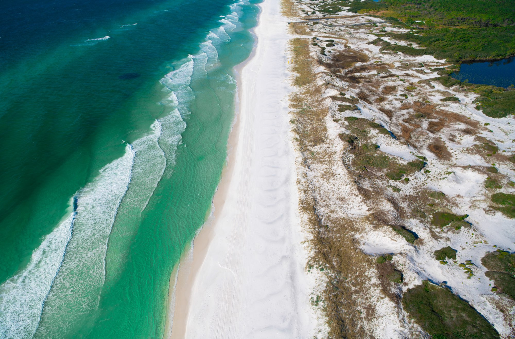 Aerial view of white sand meeting emerald water