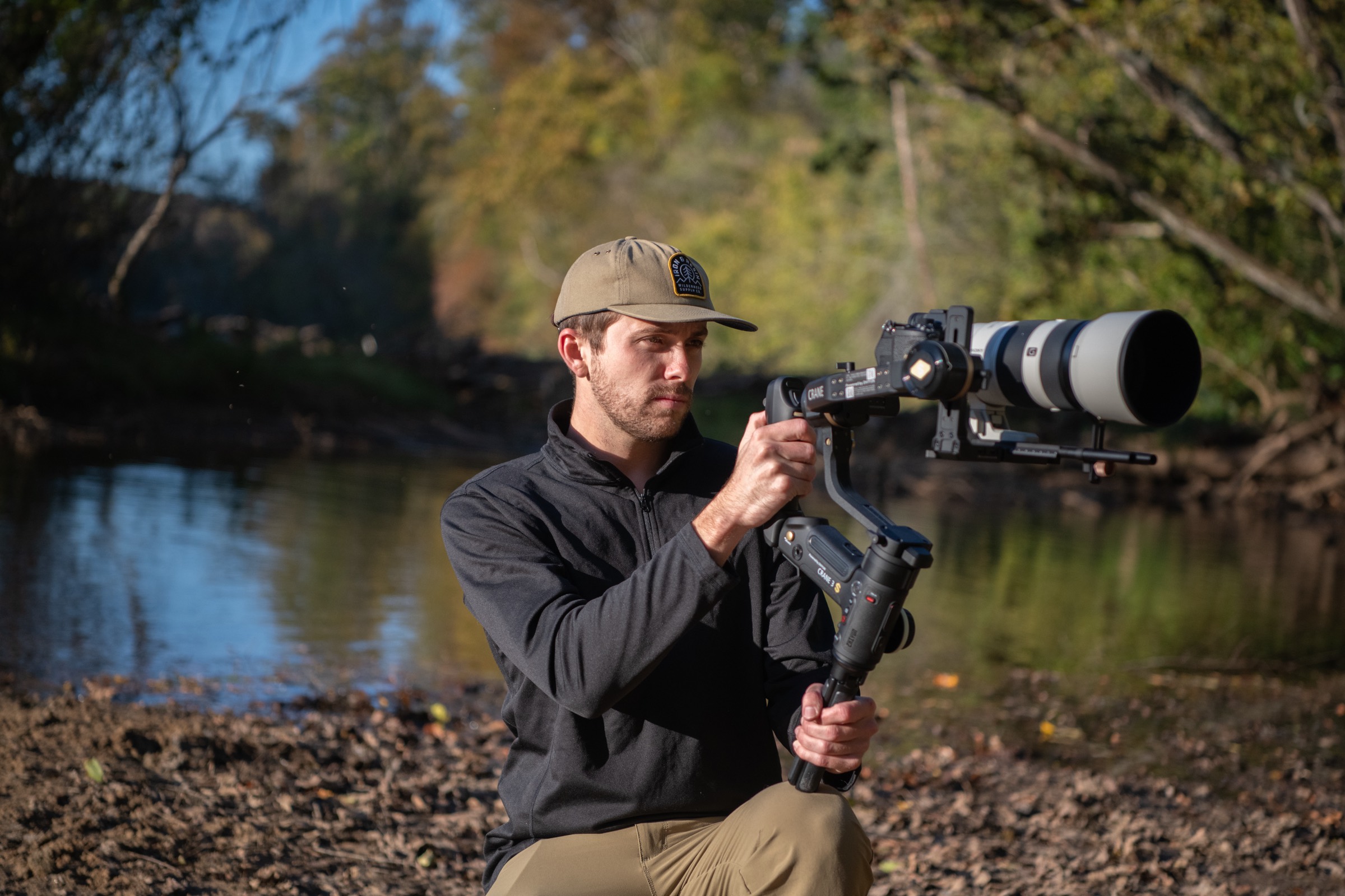 A wildlife filmmaker with a long lens on a riverbank