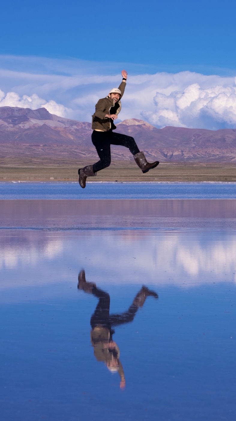 A person jumps above their reflection on a salt flat
